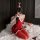 A woman poses playfully wearing a red christmas-themed holiday costume, featuring a low-cut design, suspender details, and fe...