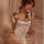 Woman wearing white retro chinese cheongsam lingerie set with black trim and adjustable side straps, sitting on bed.