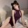 A woman poses on a bed wearing a deep purple retro chinese qipao lingerie set, featuring a halter neck design and cut-out det...