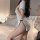 Woman wearing a white retro chinese qipao lingerie set with black trim and a high split hem, posing in a bedroom.