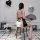 Woman wearing retro lace cheongsam lingerie, sheer mesh backless design, holding fan, seated on stool with heart balloons.