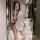 Woman in white retro lace cheongsam sleepwear with black trim, posing in a modern bathroom mirror selfie.