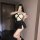 Woman posing in a sailor-themed lingerie set featuring a white crop top with black harness straps and a pleated black mini sk...