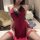 Woman wearing red lace-trimmed seductive style lingerie set by qqny, paired with matching thigh-high stockings in a cozy be...