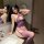 Woman modeling a seductive purple lace open-crotch suspender bodystocking with sheer mesh detailing in a modern bathroom sett...