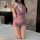 Woman in purple lace cheongsam nightgown with deep v neckline and floral details, kneeling on bed holding a rose.