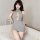 Woman modeling gray seductive knit sweater with open-chest lace-up detail, sheer high-neck bodysuit for date night.
