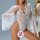 Woman modeling sheer white lace bodysuit with flared sleeves and backless design, featuring floral patterns and strappy neckl...
