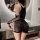 Woman modeling black lace bodysuit with mesh sleeves and sheer skirt in bathroom.