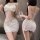 Woman wearing white lace bodysuit with open-crotch design, holding wine glass, showcasing sensual sleepwear set from front an...