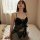 Woman wearing black lace sheer chemise with built-in pads, sitting on bed — modest yet sexy sleepwear for women.