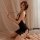 Woman kneeling on bed in black backless sleep dress with open crotch, lace trim, and choker-style straps — sexy roleplay nigh...