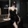 Woman in black satin cami dress with side tie, posing by bathroom sink — elegant, curvy-friendly sexy lingerie set.