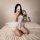 A woman poses on a bed wearing a sheer lace slip dress, holding a rose while taking a selfie. the elegant design highlights f...
