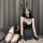 Woman in black bunny girl lingerie set with open-crotch design, sheer stockings, and lace details on sofa.