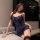 Woman wearing a seductive blue lace lingerie set with floral hair accessory, posing elegantly beside a wine glass.
