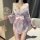 Woman in pink floral seductive maid costume lingerie set with matching robe, holding decorative fan.