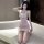 Woman kneeling in a pink lace and glitter mini dress, featuring a high neck and sheer bodice.