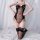 Woman kneeling on bed wearing sheer black maid lingerie set with red floral embroidery and lace thigh-high stockings.