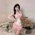 A woman poses with a teddy bear, wearing a pink maid costume set featuring sheer lace apron and sleep dress. the outfit inclu...