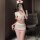 Woman wearing a seductive nurse costume set with lace details and a busty illusion design, posing in a modern room.