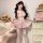 Woman modeling pink seductive nurse costume set with bow backless design, pleated skirt, and thigh-high stockings in cozy bed...