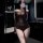 Woman in bathroom wearing sheer brown lace mesh lingerie set with long sleeves and fishnet panels.