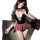 Woman in black corset-style lingerie with red plaid bow and skirt, fishnet stockings, seductive pose on dark couch.