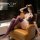 Woman in purple secretary costume lingerie set with thigh-high stockings, posing seductively on leather chair.