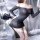 Woman wearing a black off-shoulder mini dress with fishnet stockings, posing seductively in a nightclub or live streaming set...