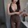 Woman wearing sheer black bodystocking with open-crotch design, holding tablet beside roses.