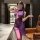 Woman wearing purple sheer lace lingerie dress with side slit and matching stockings in modern room setting.