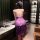 Woman wearing a purple sheer lace lingerie dress with side slit, back view in a modern room setting.