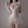 Woman wearing a white sheer lace camisole and backless slip dress with ruffled details.