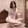 Woman wearing sheer princess sleep dress with lace backless design, chest and hip reveal, in soft bedroom setting.