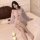 Woman wearing sheer pink princess sleep dress with lace backless design, chest and hip reveal, on bed with candles.