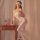 Woman wearing night seductive white bodysuit with stockings, leaning on wooden table with books and lantern.