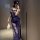 Woman in blue lace lingerie set with sheer straps, holding feather accessory, posing in mirror selfie.