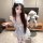 Woman wearing blue plaid sheer maid outfit with deep v lace top, mini skirt, and matching headband, holding plush bunny.
