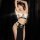 Woman in black sensual egyptian cat lady costume with hollow-out halter top, chain belt, and thigh-high slit gown for cosplay...