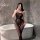 Woman in bathroom wearing black sheer full-body mesh bodystocking with open-crotch design, posing by white bathtub.