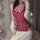 Woman wearing red lace bodysuit with open-crotch design, paired with white knit sleeves and pleated skirt.