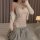 Woman wearing white lace bodysuit with open-crotch design, paired with gray sweatpants and a draped cardigan.