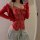 Woman wearing red lace bodysuit with open-crotch design, paired with gray sweatpants and a red cardigan.