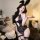 Woman wearing black lace bodysuit with bunny ears, sheer panels, and garter straps in cozy bedroom setting.