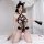 Woman wearing black lace bodysuit with cat ears, sheer mesh and cut-out design, holding a fan on white bed.
