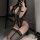 Woman kneeling in black lace bodysuit with gold chains, sheer mesh panels, and matching stockings. sensual sleepwear set.
