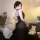 Woman wearing black sensual lace mesh slip dress - pure temptation sleepwear set, posing on bed with plush toys and pillows.