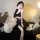 Woman wearing black sensual lace mesh slip dress, elegant nightgown with floral hair accessory, cozy bedroom setting.