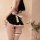 Woman wearing black sensual lace sleep dress with white ruffles and bow, paired with matching garter thigh-highs.